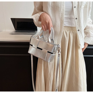 Close-up of metallic silver woven tote bag with round handles and detachable strap