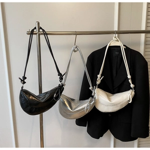 Close-up of metallic crescent bags in black, silver and white with knotted strap detail