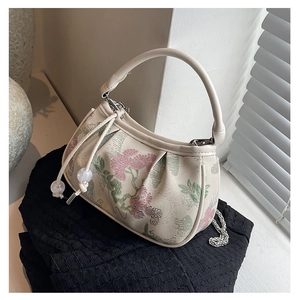 Detail view of floral embroidery and pearl drawstring on beige crossbody handbag