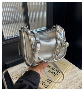 Détail d'un sac à main argenté avec motif texturé et poignée en chaîne métallique