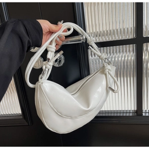 Detail of white half-moon shoulder bag with knotted strap and silver metal accents