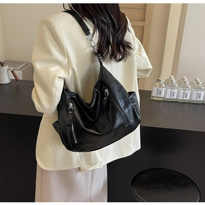 Model wearing a large black vintage motorcycle tote bag with silver zipper and wrinkled texture