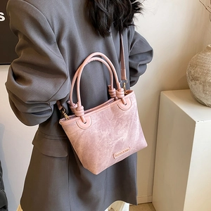 Pink matte trapezoid bucket bag with knotted handles and adjustable shoulder strap