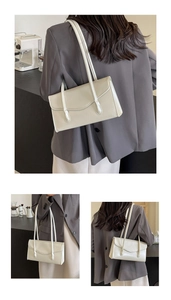 Detail of minimalist cream leather shoulder bag with sleek flap and thin straps