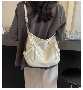 Detail of cream white bucket bag with decorative bows and zipper in street style