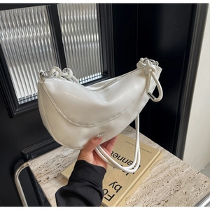 Close-up of a white crescent moon shoulder bag with polished PU leather and silver rings
