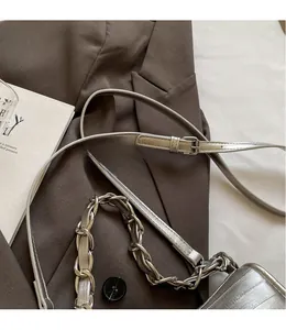 Détail de la bandoulière réglable et chaîne argentée sur le sac à main embossé