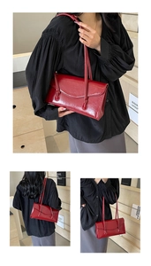 Macro view of deep red glossy patent leather handbag with delicate thin shoulder straps