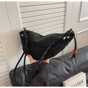 Détail du sac hobo noir avec gaufrage lune et perle orange sur la bandoulière nouée