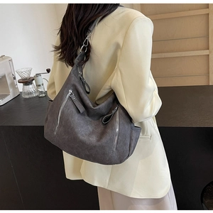 Deep grey vintage tote bag with zipper details worn by a model in a modern cafe setting