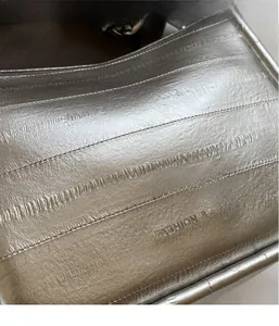 Détail du tissu métallique argenté et du logo FASHION & BAGS sur le sac à bandoulière