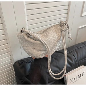 Détail du sac bandoulière gris clair avec bandoulière nouée et texture gaufrée moderne