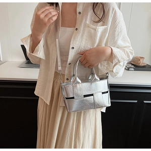 Silver metallic woven handbag styled with white outfit in an elegant office setting