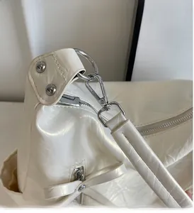 Detail of white glossy leather bucket bag showing shiny silver hardware and metal zipper
