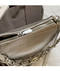 Gros plan sur la fermeture éclair en métal poli et le cuir texturé de ce sac carré