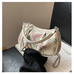 Detail showing the floral embroidery and beaded handle on a cream moon bag