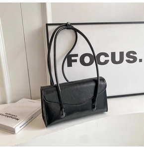 Detailed view of black patent leather underarm bag with glossy oil-wax finish and flap closure