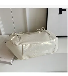 Detail of soft cream bucket bag showing lychee grain texture and ribbon decoration