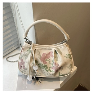 Detailed view of embroidery flower pattern and pleats on a beige small square handbag