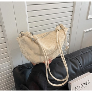 Détail du sac demi-lune crème avec texture gaufrée et bandoulière à cordon