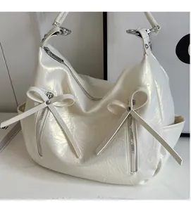 Detail of pearl white bucket bag with pleated texture and decorative bows and zippers