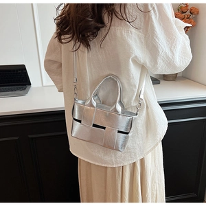 Detail of silver metallic woven handbag with wide straps and metal hardware