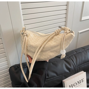 Détail du sac croissant crème avec motif crocodile et nœud sur la bandoulière réglable