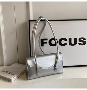 Close-up of a silver minimalist shoulder bag with smooth metallic texture and dual straps
