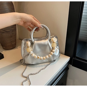 Détail d'un sac nuage plissé argenté avec perles d'ambre et chaîne métallique fine