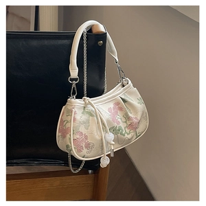 Detail of floral embroidery on a white crossbody bag with delicate pearl bead accents