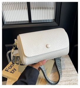 Close-up of white pebble-textured crossbody bag with black and white geometric wide strap