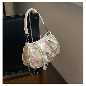 Close-up of floral embroidery detail with silver chain strap on vintage handbag