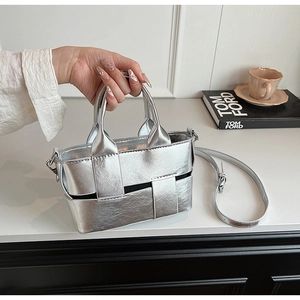 Detail of silver woven mini tote bag featuring metallic texture and adjustable shoulder strap