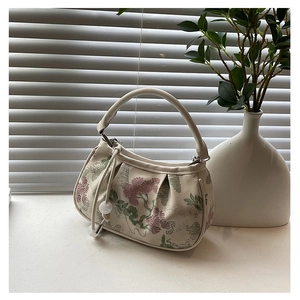 Close-up of beige crossbody bag with floral embroidery and pearl drawstring detail