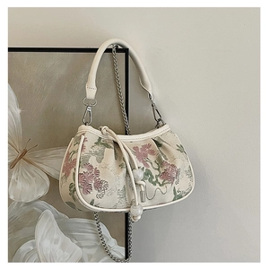 Detailed view of floral jacquard handbag with cream leather handle and silver chain