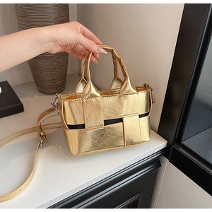 Detailed macro view of a gold woven mini handbag with crossbody strap and dark lining