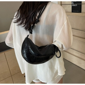 Detail view of black oiled leather crescent bag with stylish knot shoulder strap design