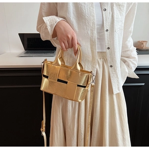 Close-up of small golden woven leather handbag with metallic texture and crossbody strap