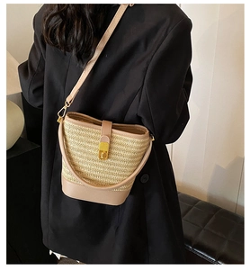 Detailed view of woven straw bucket bag with khaki leather trim and gold twist lock