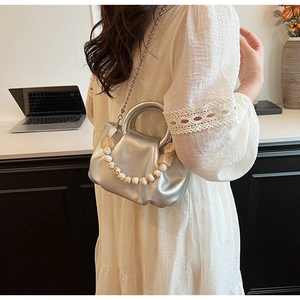 Détail du sac plissé argenté avec de grandes perles et une fine bandoulière en chaîne métal