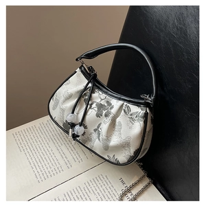 Detail of embroidered small square bag with floral patterns and silver chain accent