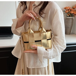 Close-up of golden woven handbag with cross-braided leather texture and metal buckle