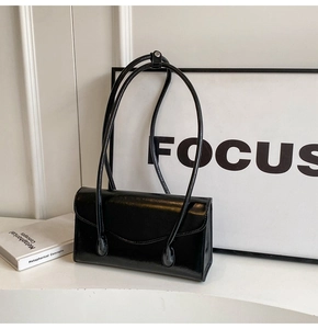 Detail of a vintage black glossy leather shoulder bag with sleek minimalist straps