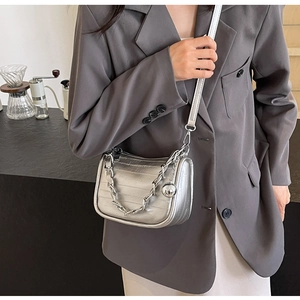 Détail du sac bandoulière argenté métallisé avec chaîne et pendentif rond en métal