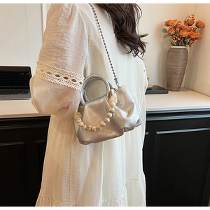 Sac nuage plissé argenté avec poignée en perles et chaîne en métal porté par un mannequin