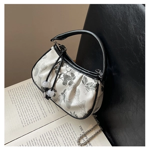Detail of Chinese style embroidery on a black and white mini bag with metal chain strap