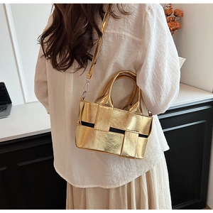 Close-up of gold woven handbag with detachable leather shoulder strap on a model