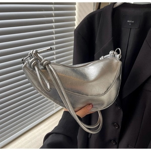 Detail of silver crescent bag featuring crinkled metallic texture and knotted strap design
