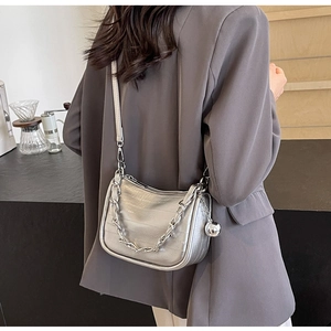 Sac bandoulière argenté à motif crocodile avec chaîne porté sur un blazer gris