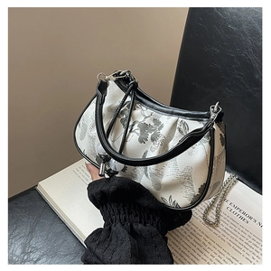 Close-up of embroidered floral handbag with silver metal chain on a vintage book